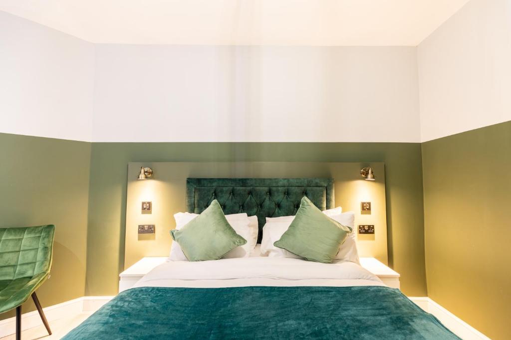 伦敦The Chapter Hotels - Finsbury Park的卧室配有一张带绿床单和枕头的大床。