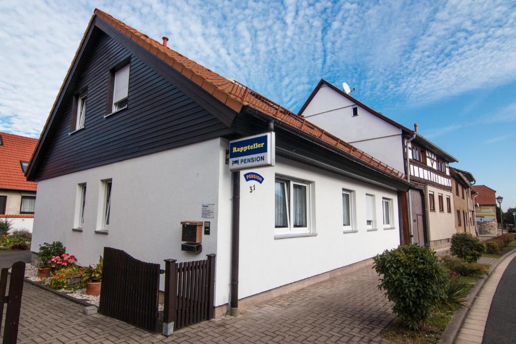 ApfelstädtPension-Rappteller的街上有黑屋顶的白色房子