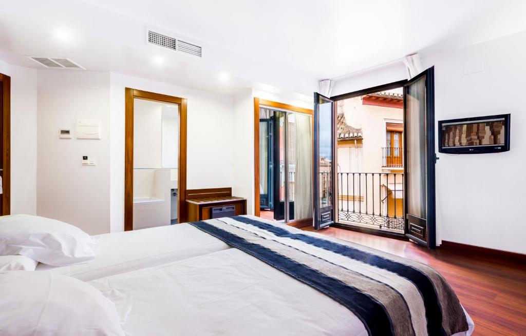格拉纳达Monjas del Carmen Hotel的一间带大床的卧室和一个阳台