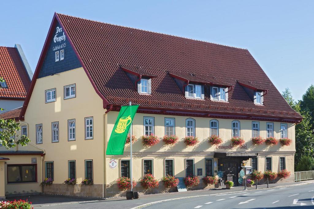 Rödental戈洛斯彻布朗酒店&旅社的红色屋顶的大型黄色建筑