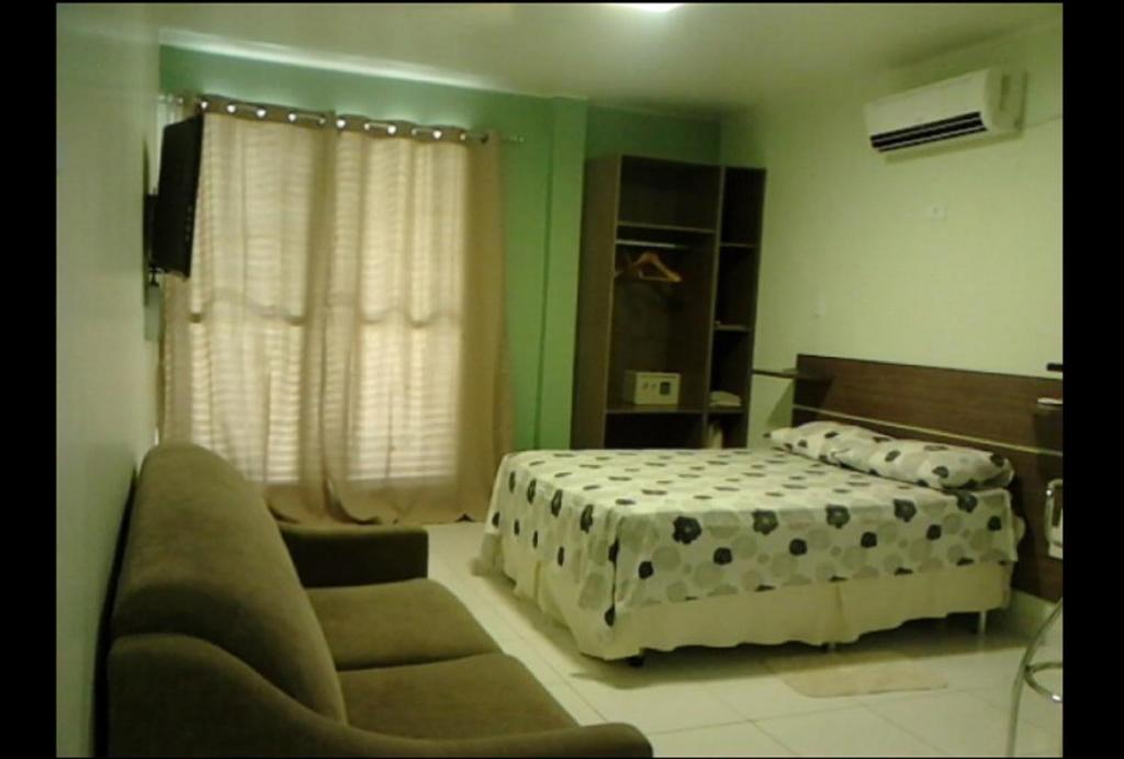 马瑙斯Ajuricaba Suites 1的一间卧室配有一张床和一张沙发