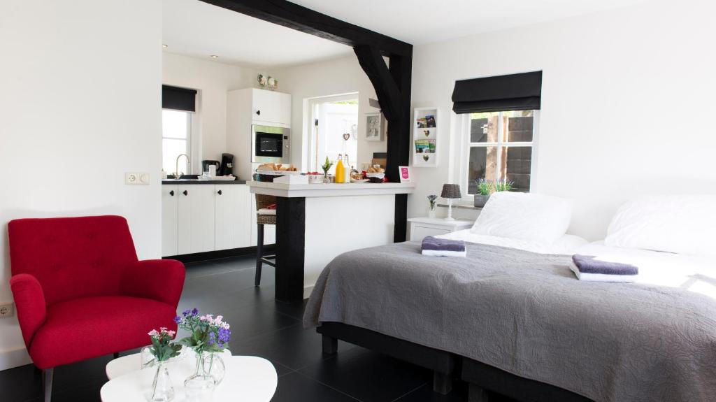 海伦多伦Bed and Breakfast De Reggestee的一间卧室配有一张床和一张红色椅子,还设有一间厨房