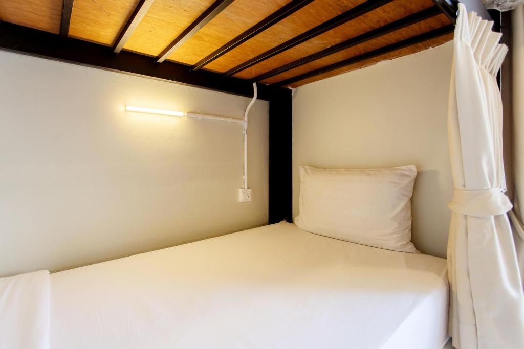 乔木提恩海滩Nomad Plus Life Hostel Pattaya的小型客房的一张床位,设有天花板