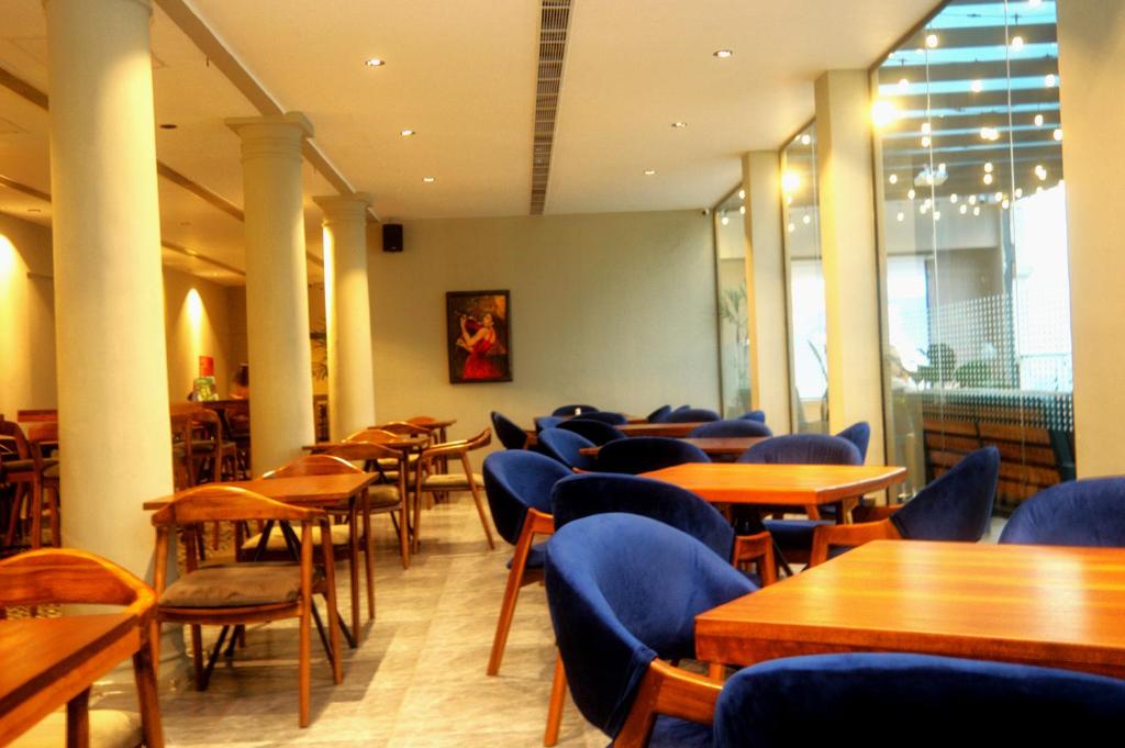 科伦坡Fairway Colombo - Sri Lanka&#39;s First Hotel With Robot Technology的有木桌和蓝色椅子的餐厅
