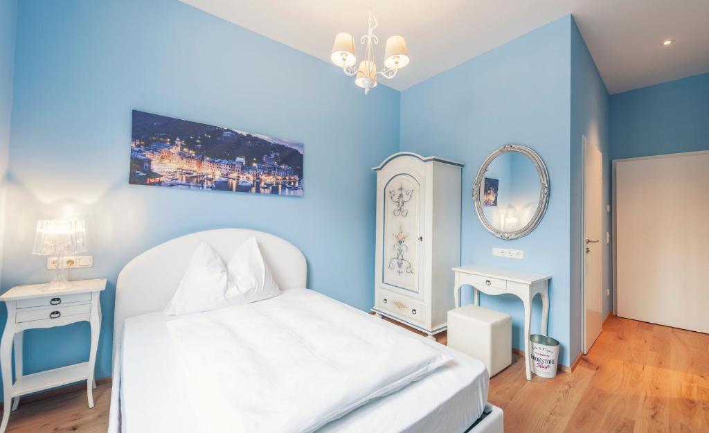 Peggau拉库齐纳酒店及餐厅的一间蓝色的卧室,配有白色的床和镜子