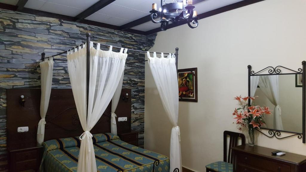 博柳略斯帕尔德尔孔达多埃尔利里奥餐厅及旅舍的一间卧室配有一张带窗帘和石墙的床。