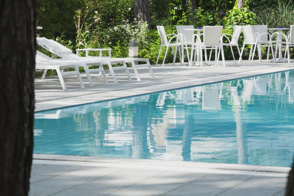 利尼亚诺萨比亚多罗加拉加斯酒店的一组坐在游泳池旁的白色椅子