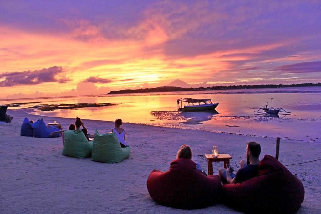 吉利阿尔班兰简易别墅的一群坐在海滩上的人,看着日落