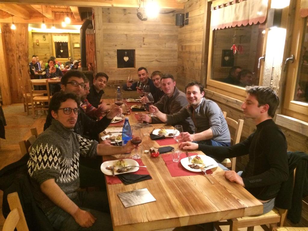 圣马蒂诺Rifugio Luna Nascente的一群男人坐在餐馆的桌子旁