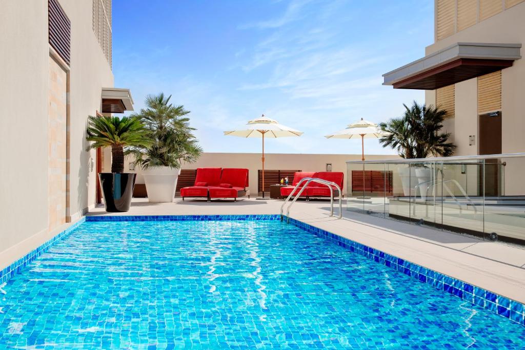 多哈多哈首府中心罗塔纳酒店的大楼内一个带椅子和遮阳伞的游泳池