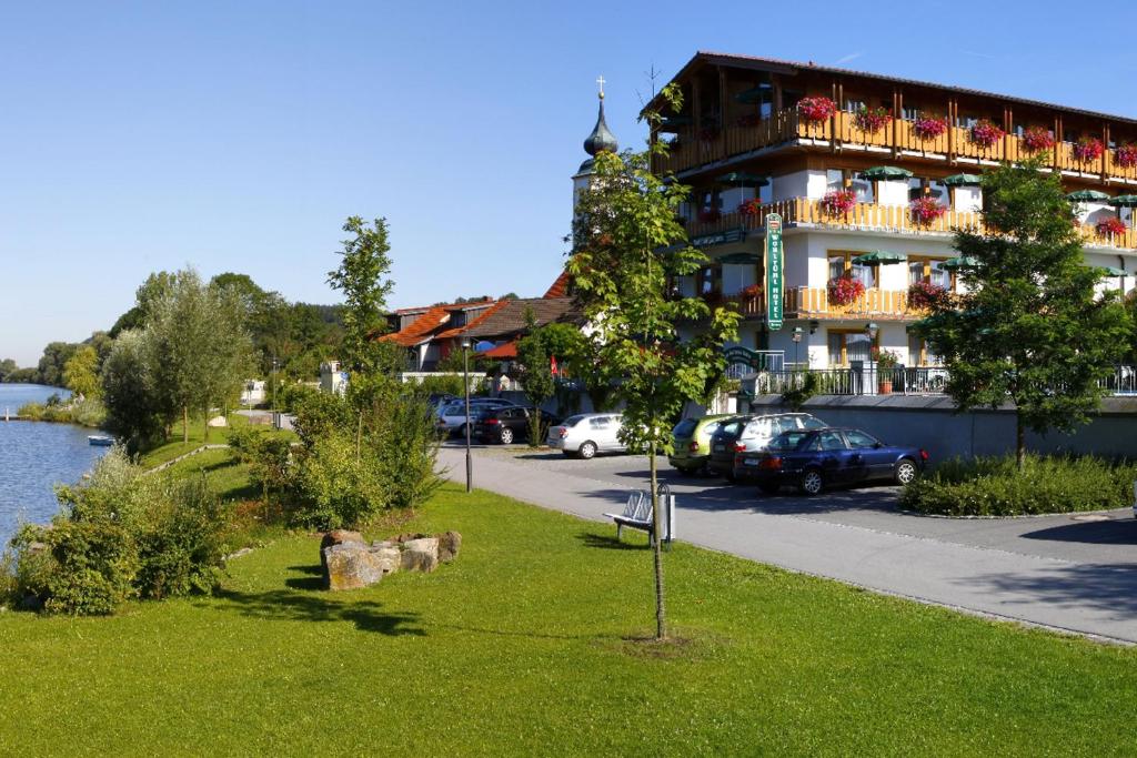 WindorfHotel Restaurant Zum Goldenen Anker mit Hallenbad & Wellnessbereich的停泊在河边停车场的汽车建筑