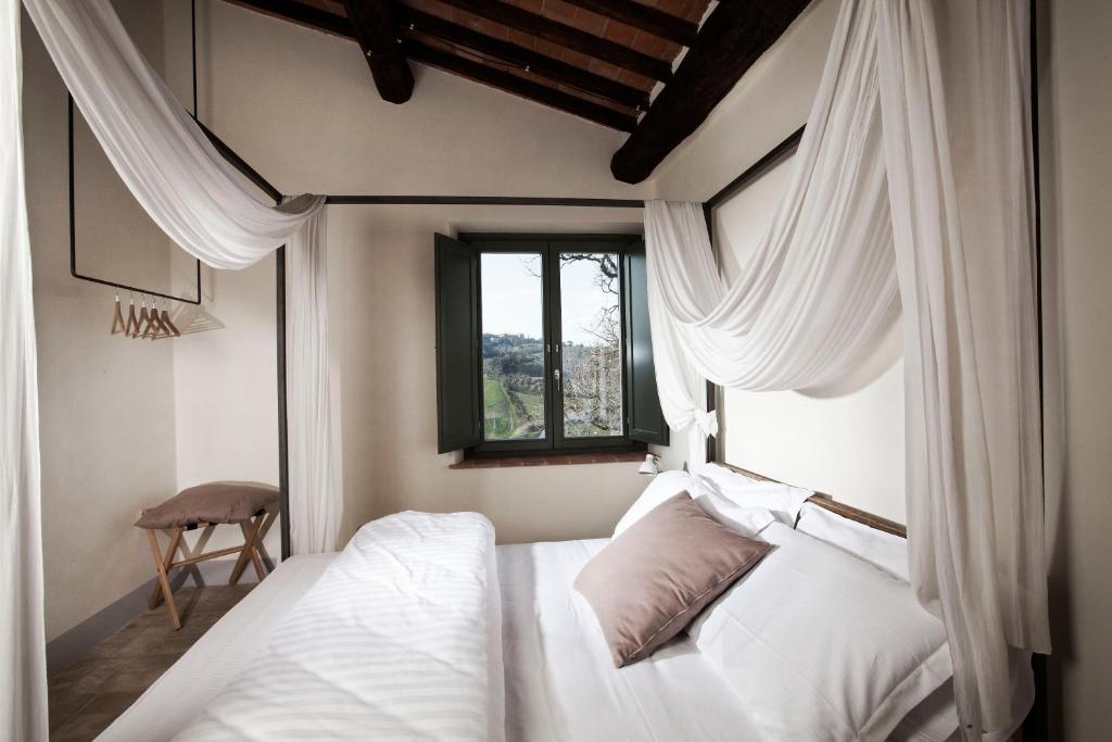 蒙特普齐亚诺萨尔奇托怀恩豪斯旅馆的卧室配有带白色窗帘的床和窗户。