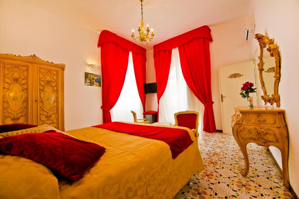 阿马尔菲Residenza Sole Amalfi的一间卧室配有红色窗帘、一张床和一个梳妆台