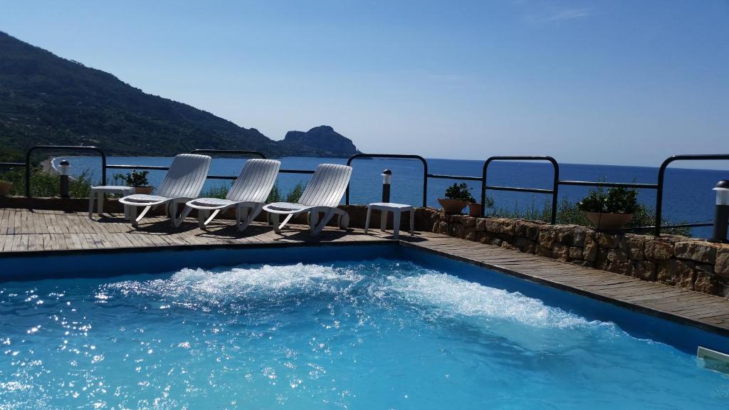 切法卢CH Exclusive Apartments的一个带椅子的游泳池,背景是大海