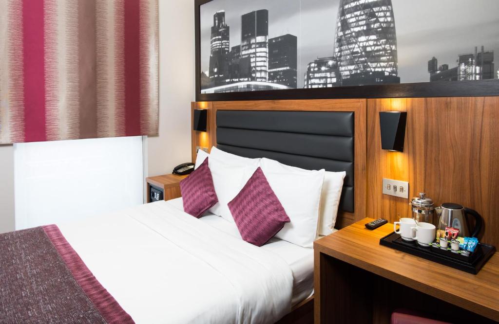 伦敦London Court Hotel的酒店客房配有一张带白色床单和紫色枕头的床。