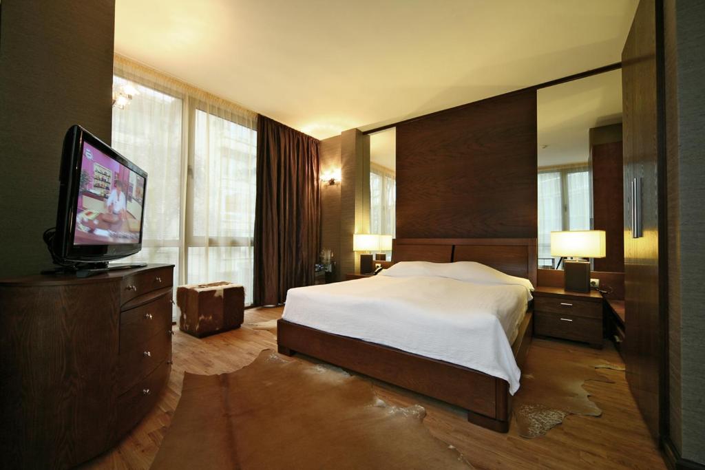 普列文普列文城市酒店的一间卧室配有一张床和一台平面电视