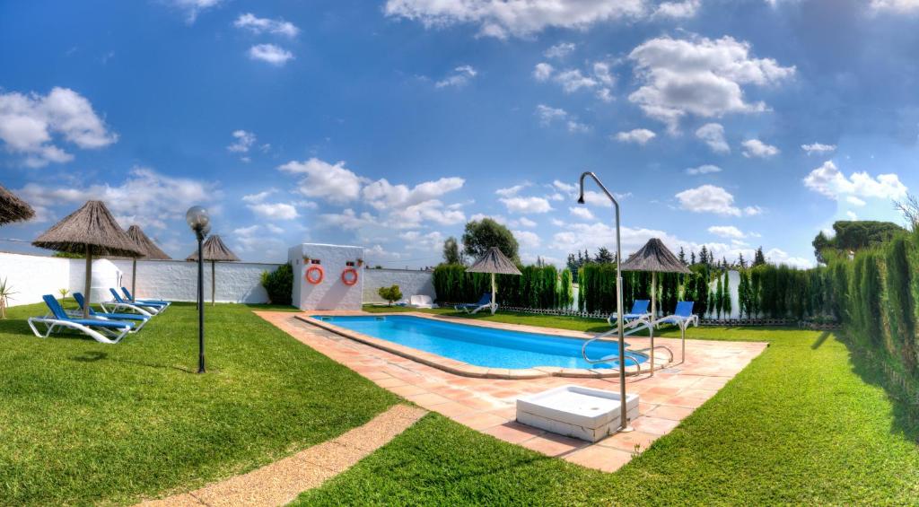 科尼尔-德拉弗龙特拉Hacienda los Majadales的庭院内的游泳池,配有椅子和遮阳伞