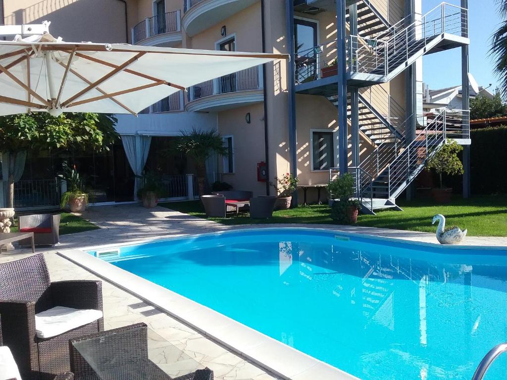 科林加谷洛酒店的一座带遮阳伞的游泳池位于大楼旁