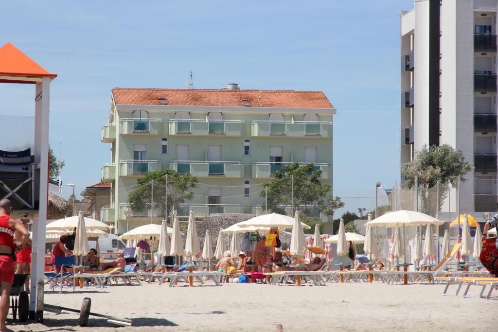 里米尼罗萨蒂酒店的一个带椅子和遮阳伞的海滩和一座建筑