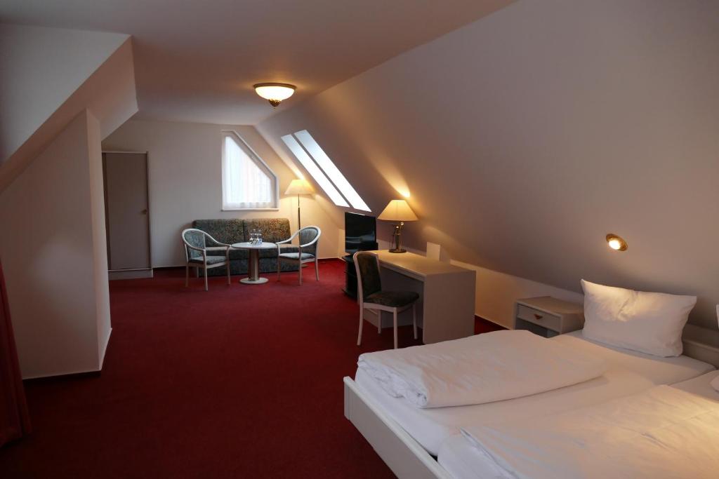 格赖夫斯瓦尔德Hotel Am Dom的酒店客房带一张床、一张桌子和椅子