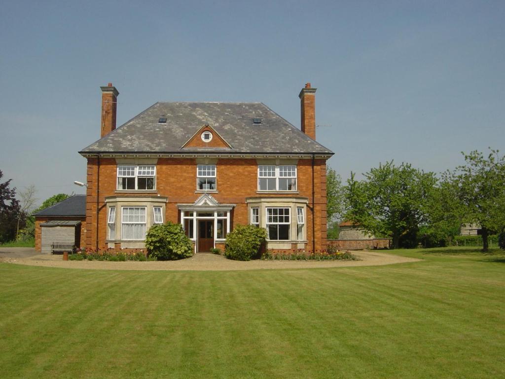 米尔顿凯恩斯Furtho Manor Farm的一个大砖房,有大草地庭院