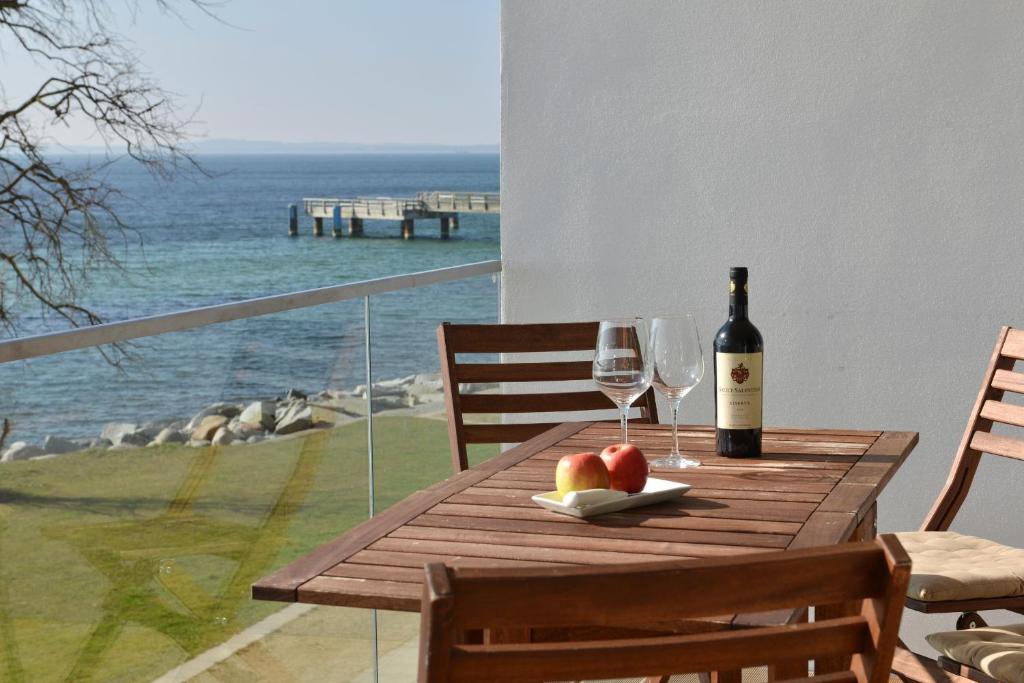 萨斯尼茨Penthouse Ostseeresidenz的一张木桌,配有一瓶葡萄酒和两杯酒