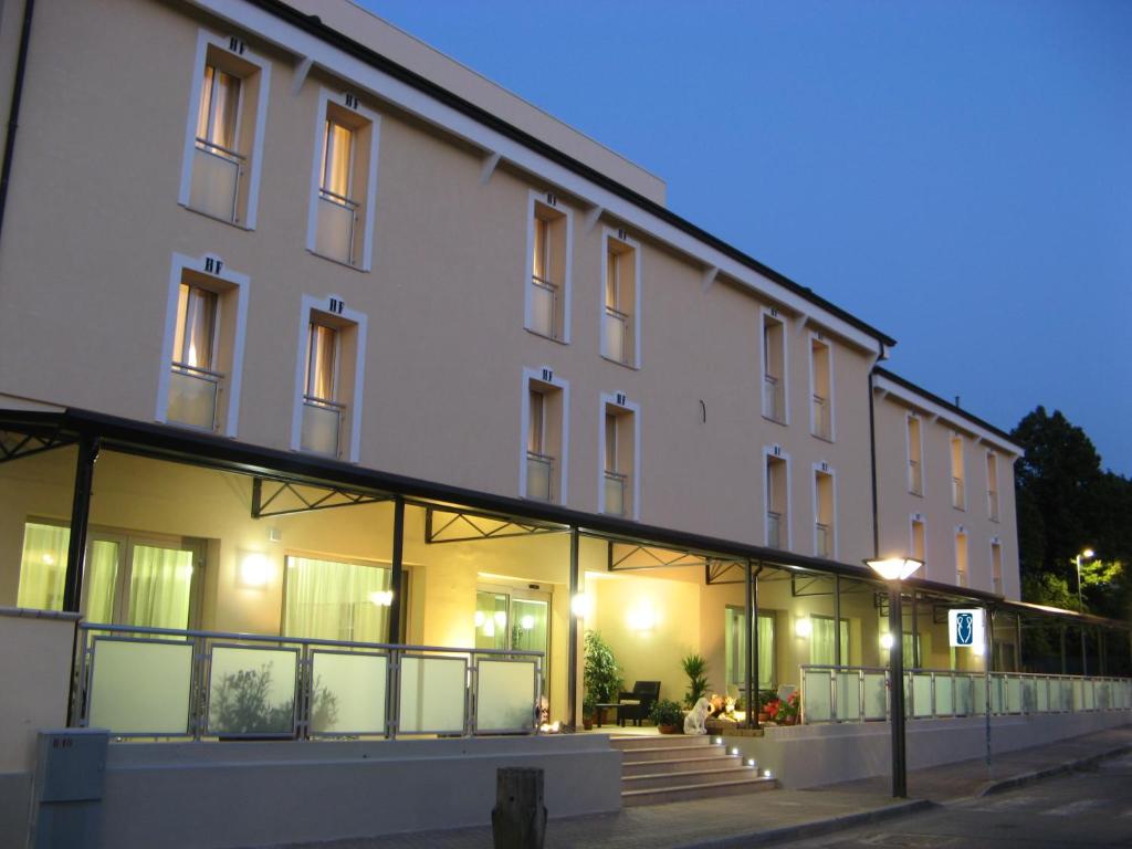 法塔特米Hotel Fontanelle的一座白色的大建筑,晚上有玻璃窗