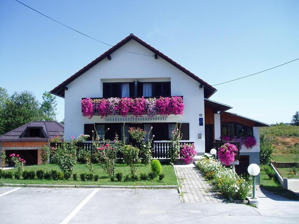 格拉博瓦茨Guest House Borić的白色房子的一侧有鲜花