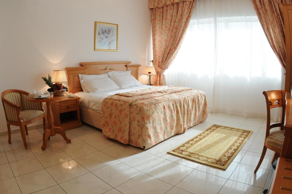 阿布扎比Uptown Hotel Apartments Abu Dhabi by Gewan的一间卧室配有一张床、一张桌子和一个窗户。