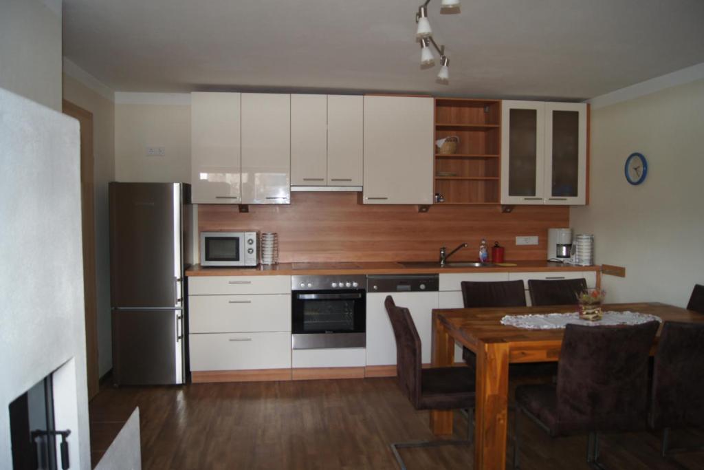 卡普伦Appartement Felix的厨房配有白色橱柜、木桌和用餐室