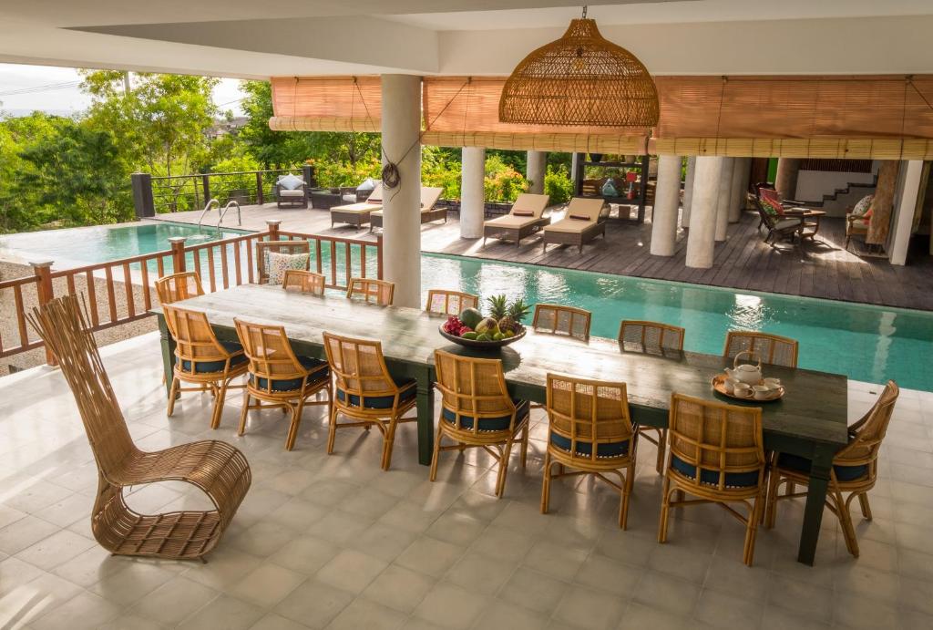 乌鲁瓦图巴厘岛阿迪拉别墅的一个带桌椅的庭院和一个游泳池