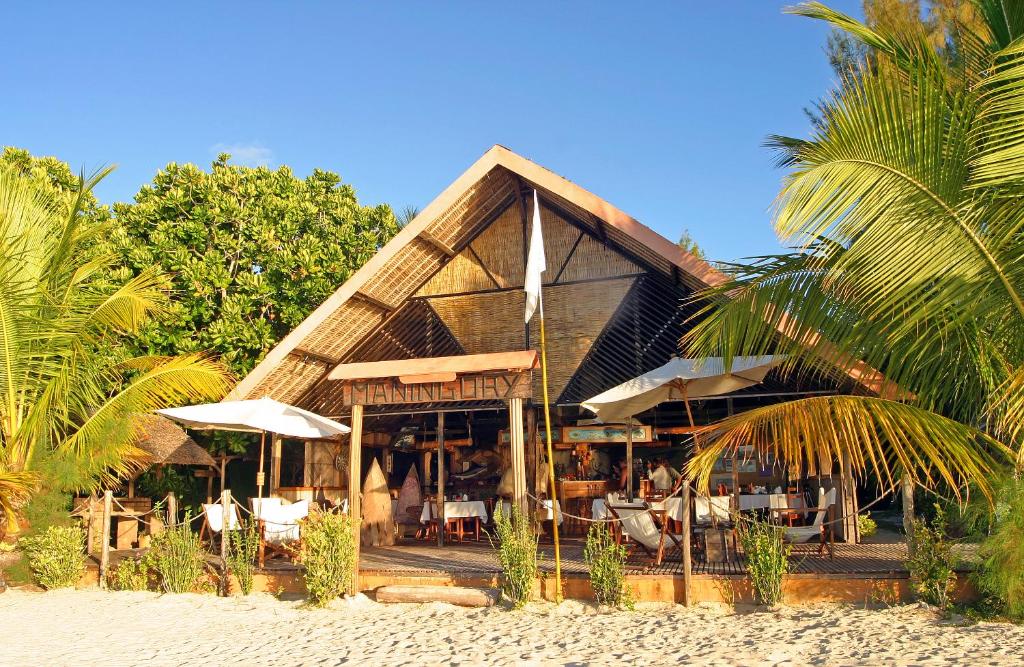 Ile aux Nattes曼尼格里酒店的海滩上设有1间带椅子和遮阳伞的餐厅