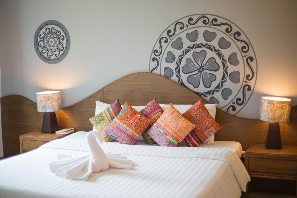 清迈清迈鸦片公寓式酒店的一间卧室配有一张带色彩缤纷枕头的大床