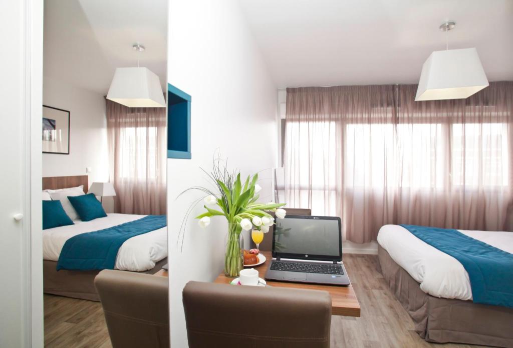亚眠Odalys City Amiens Blamont的酒店客房设有两张床和一张书桌上的笔记本电脑