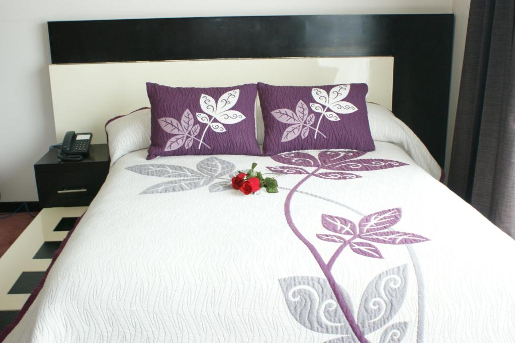 底拉斯卡拉坎卡利商务套房酒店的一张带紫色枕头和白色棉被的床