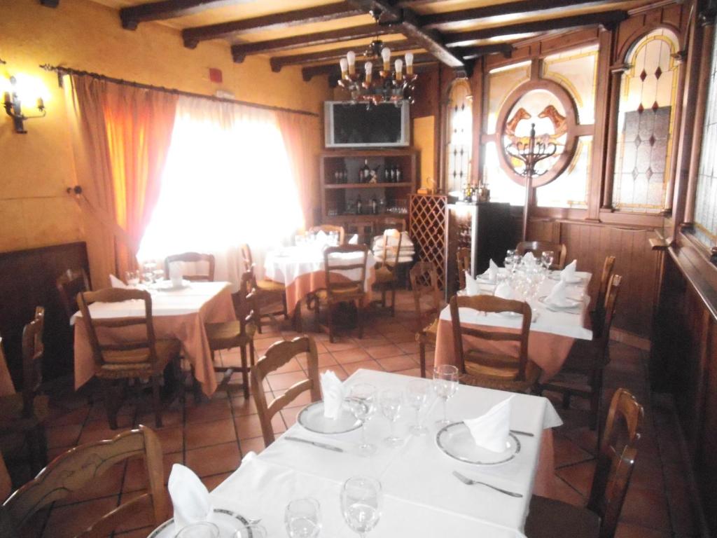 YepesHostal Los Galgos的一间设有白色桌椅和窗户的用餐室