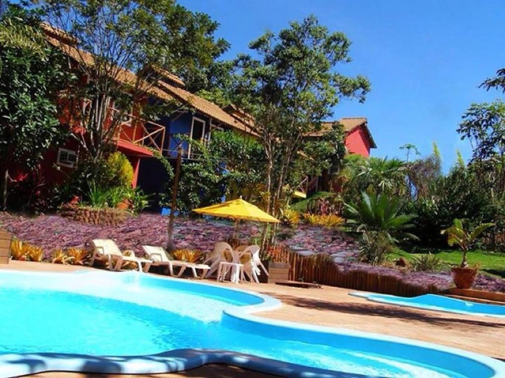 伦索伊斯Mirante de Lençóis的一个带椅子和遮阳伞的游泳池以及一间房屋