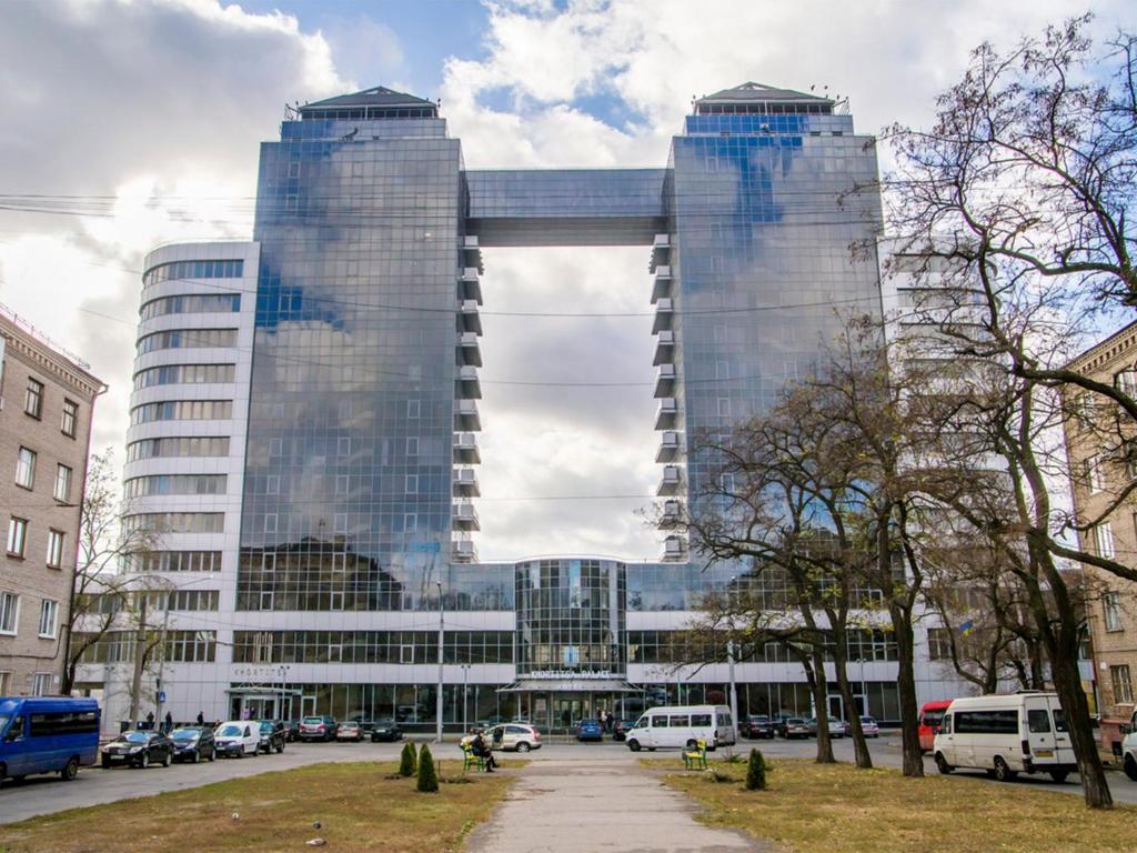 扎波罗热Khortitsa Palace Hotel的一座高大的建筑,在城市里装有镜子的窗户