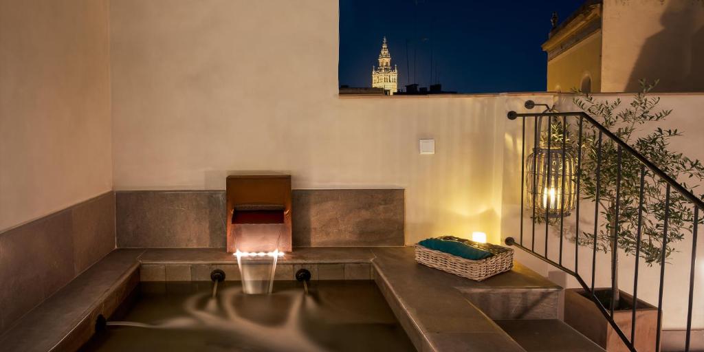 塞维利亚科拉尔精品酒店 - 德尔雷伊的一座在晚上在阳台上设有热水浴缸的建筑