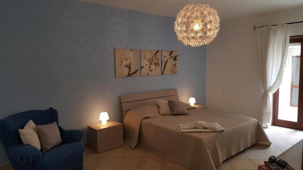 CaltabellottaCasa Sofia的一间卧室配有一张床、一把椅子和一个吊灯。