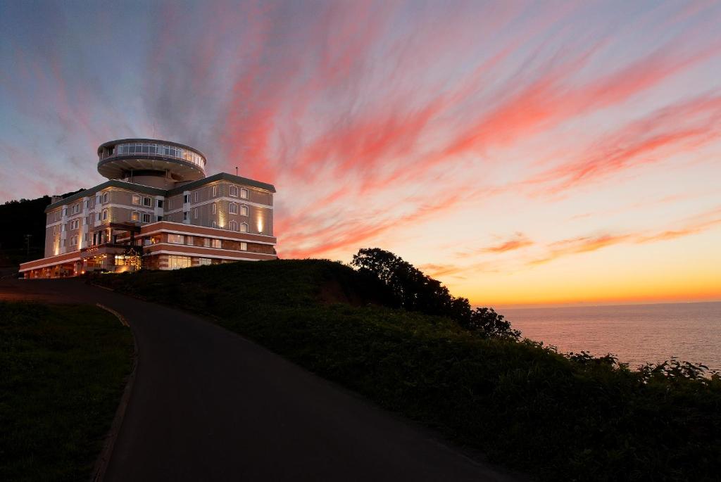 小樽小樽东大宫酒店的日落时分在海边的山丘上的建筑