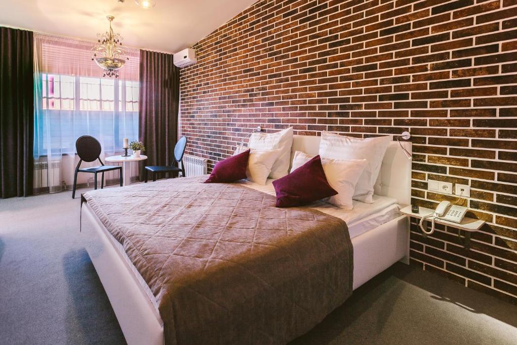 秋明Simpatico Apart-hotel Tyumen centre的一间卧室设有一张带砖墙的大床