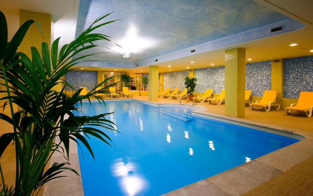 布迪皮拉格斯Playas de Liencres - Hotel & Apartamentos的酒店的大型游泳池设有黄色椅子