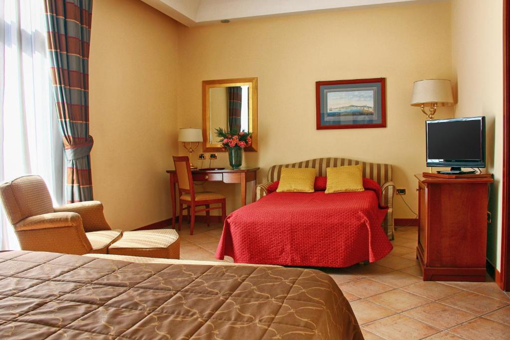 那不勒斯那不勒斯里奇米尼商务酒店的酒店客房,配有床和电视