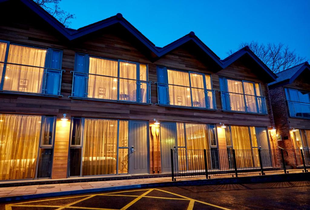 切斯特河滨客房船屋酒店 的一座大型木制建筑,晚上设有大窗户