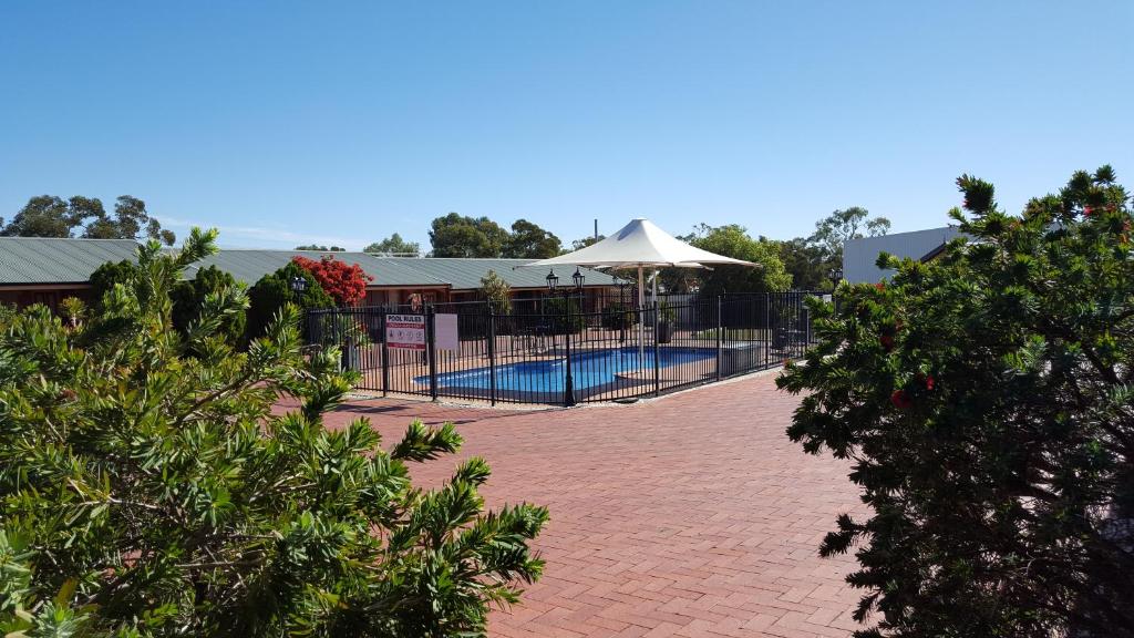 布罗肯希尔Gateway Motor Inn - Self Check-In的一个带围栏和遮阳伞的游泳池