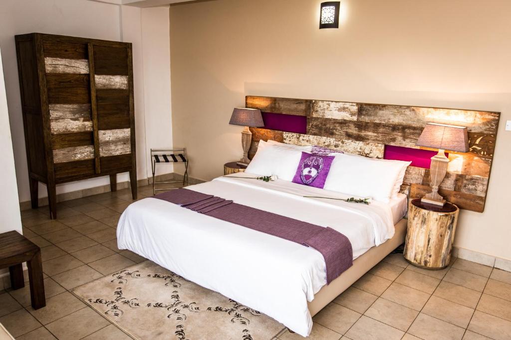 弗里敦The Swiss Hotel Freetown的一间卧室配有一张紫色色调的大型白色床。