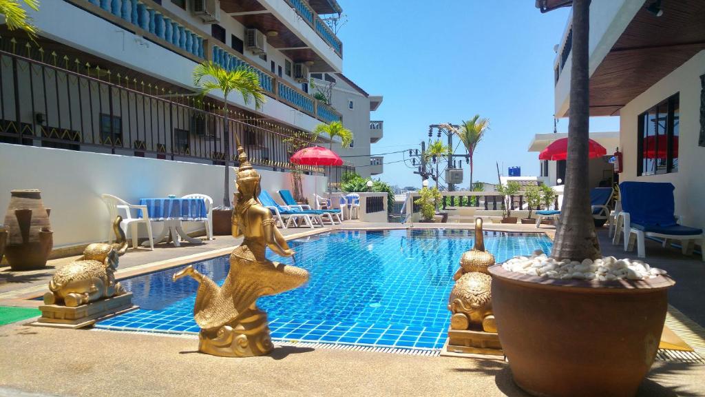 芭东海滩蓝天公寓式酒店的一座带金雕的游泳池,位于大楼旁