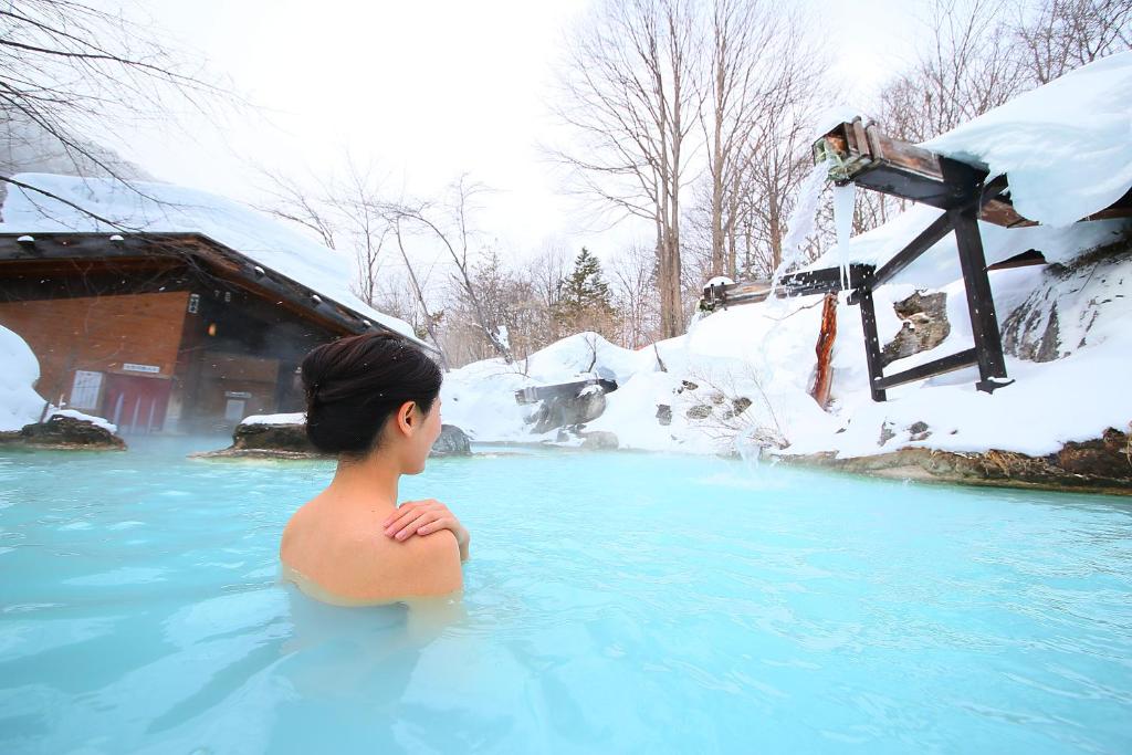 松本泡汤旅馆的在一个雪中热水浴缸里的男孩