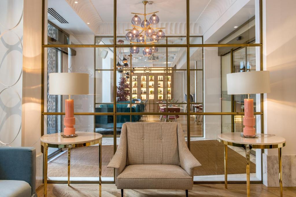 马德里文奇中心酒店的大堂设有椅子、两张桌子和吊灯